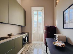 a kitchen with a refrigerator and a table in it at Iconic Ortigia Residence - CarAccess PrimeLocation DiningGuide in Siracusa