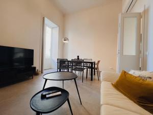 a living room with a couch and a table with chairs at Iconic Ortigia Residence - CarAccess PrimeLocation DiningGuide in Siracusa