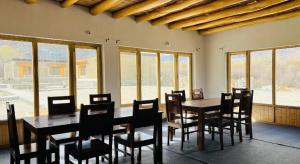a dining room with tables and chairs and windows at Hunder Tamarix Resort in Hundar