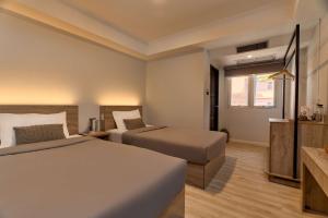 a hotel room with two beds and a window at Thapae60 Mini Hotel in Chiang Mai
