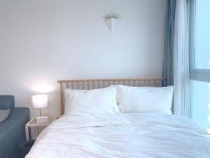 a bedroom with a white bed with a window at House of Hyuni in Busan