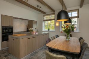 a kitchen with a wooden table and a dining room at Welcome in - Vakantiehuis Boerderij Molenhof met een riante tuin en rustig gelegen in Heinkensand