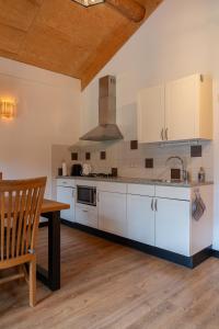 a kitchen with white cabinets and a wooden table at Boomgalows De Roestelberg in Kaatsheuvel +28 photos