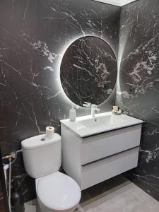 a bathroom with a toilet and a sink and a mirror at Tranquil Oceanfront Escape, One-Bedroom Haven in Mijas