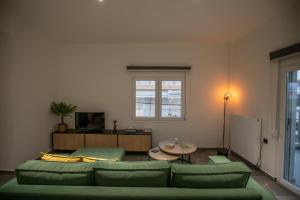 a living room with a green couch and a table at Anesis Apartment in Karditsa