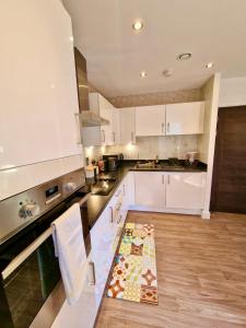 a kitchen with white cabinets and a wooden floor at The Mirrored House in Kent