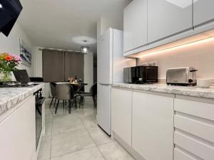 a kitchen with white cabinets and a dining room at Borage House- Spacious & Stylish 3BR 18 min from Gatwick Airport, CRAWLEY in Ifield +59 photos