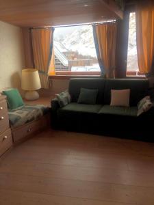 salon z zieloną kanapą i oknem w obiekcie Profumo di Legno a Cielo Alto La Coquille w mieście Breuil-Cervinia