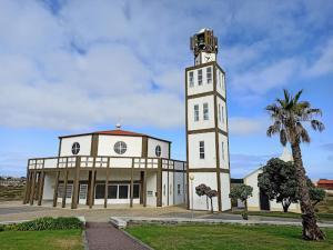 a building with a clock tower next to a palm tree at Alojamento Emílio T1 in Gafanha da Encarnação