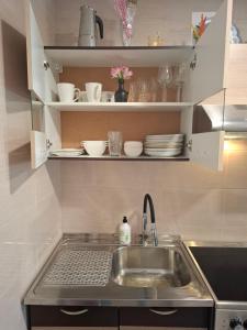 a kitchen sink with plates and dishes on shelves at Apartamentai Auris in Druskininkai
