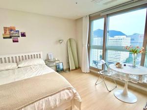 a bedroom with a bed and a table and a large window at House of Hyuni in Busan