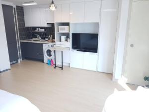 a kitchen with white cabinets and a sink and a dishwasher at House of Hyuni in Busan