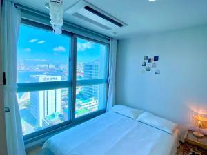 a bedroom with a bed and a large window at House of Hyuni in Busan