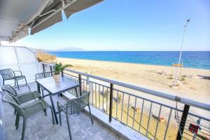 a balcony with a table and chairs and a beach at House Kohili in Nea Vrasna