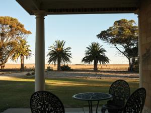 a table and chairs on a porch with a view of the beach at Forgo tten Paddock in Maitland