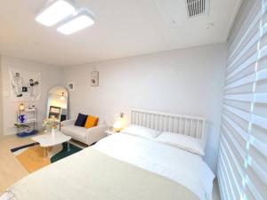 a bedroom with a white bed and a couch at House of Hyuni in Busan