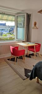 a dining room with a table and two red chairs at Le Coquet in Lannion +12 photos
