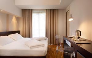 a hotel room with a white bed and a desk at Astoria Resort in Riva del Garda