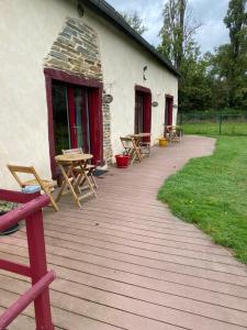 a wooden deck with picnic tables and a building at La Malcotais in Noyal-Châtillon-sur-Seich