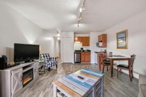 a living room with a flat screen tv and a table at 105 Pointes North Inn in Charlevoix