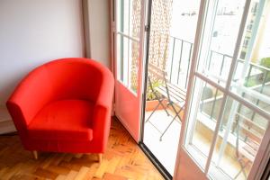 a red chair sitting in a room next to a window at Alvalade II Airport Guest House in Lisbon