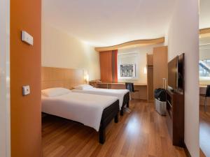 a hotel room with two beds and a flat screen tv at ibis Stuttgart Airport Messe in Leinfelden-Echterdingen