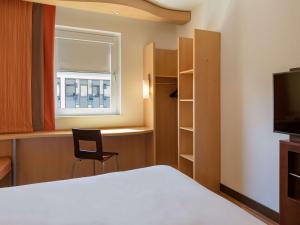 a room with a bed and a chair and a window at ibis Stuttgart Airport Messe in Leinfelden-Echterdingen