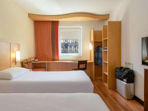 a hotel room with two beds and a desk at ibis Stuttgart Airport Messe in Leinfelden-Echterdingen