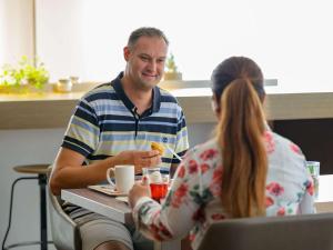 a man and a woman sitting at a table eating food at ibis Stuttgart Airport Messe in Leinfelden-Echterdingen