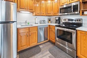 a kitchen with wooden cabinets and stainless steel appliances at ML184 1st Floor No Elevator EZ Gated Parking WiFi in Snowshoe