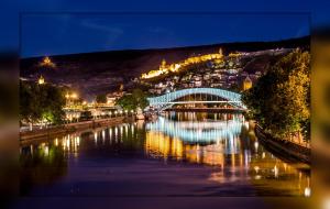 a bridge over a river with a train on it at River Side Hotel Tbilisi in Tbilisi City