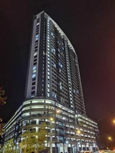 a tall building is lit up at night at JQ Sea & Sunset view, 25th floor, Swimming Pool, byMGSabah in Kota Kinabalu