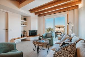 a living room with a couch and chairs and a tv at Dolce Luxury Villas in Psarou