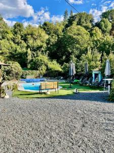 a swimming pool with a bench and umbrellas at Cortijo Luz de la Sierra in Dúdar