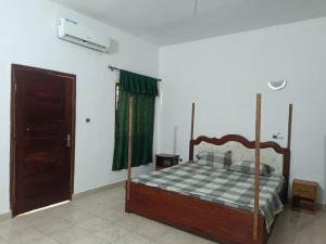 a bedroom with a bed and a green curtain at Lumineuse loge privée de 4 chambres en air de plage in Cotonou