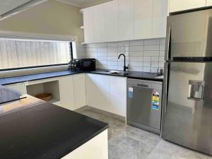 a kitchen with a stainless steel refrigerator and white cabinets at Granny Guest House Sydney Blue Mountain in Kingswood +6 photos
