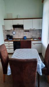 una cocina con mesa y sillas y una cocina con armarios blancos. en Ferienwohnung am Wildgehege bei Walsrode, en Walsrode