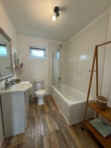 a bathroom with a tub and a toilet and a sink at Acogedora Casa Los Canelos in Puerto Varas +37 photos