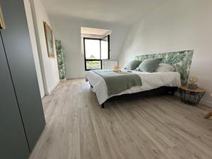 a bedroom with a bed and a wooden floor at Les mouettes, SPA privé, 600m de la plage, Formule tout inclus in Erdeven