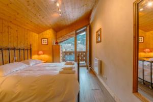 a bedroom with a bed and a large window at Luxury Family Ski Chalet - Jacuzzi BBQ - Near Lake Golf - Multipass access 60 Summer activities - Sleep 10 in Les Gets
