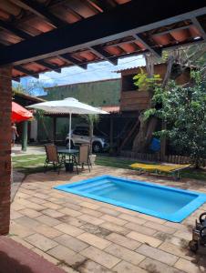 a swimming pool in a patio with a table and an umbrella at Casa em São Pedro da Aldeia in São Pedro da Aldeia