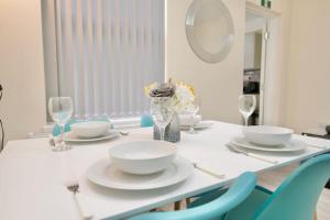 a dining room table with white plates and blue chairs at Cosy 1Bed Flat with Garden, Parking & Free Netflix in Coventry +16 photos