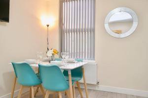 a dining room with a white table and blue chairs at Cosy 1Bed Flat with Garden, Parking & Free Netflix in Coventry