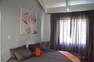a bedroom with a bed with an orange pillow on it at Abundant Grace in Montagu