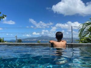 a man in a swimming pool looking out at the water at Villas Tangarane in Les Trois-Îlets