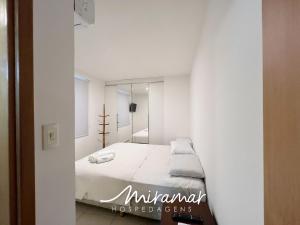 a white bedroom with a bed and a mirror at Le Parc - Manaíra in Tambaú