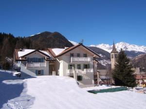 a house in the snow with mountains in the background at VALDISOLE-home in Ossana