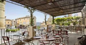 a patio with tables and chairs on a balcony at Les Beaumettes, villa provençale à deux pas de Gordes in Beaumettes