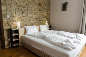 a bed in a bedroom with a stone wall at VIP Apartments Sofia in Sofia