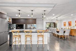 a kitchen and dining room with a bar with stools at Luxury Hunter Valley Acreage - Heated SwimSpa - Mountain Views - Pool Table - Fire Pitt in Millfield +42 photos
